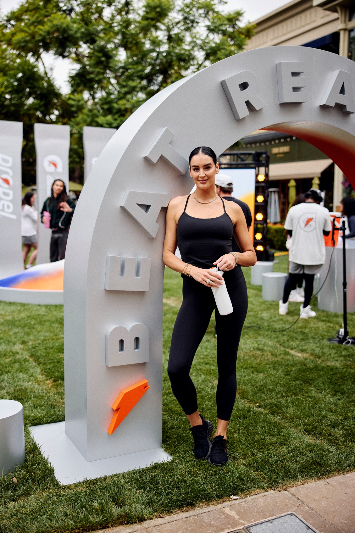 Athlete posing beneath a Beat Real Life arched installation on a lawn activation