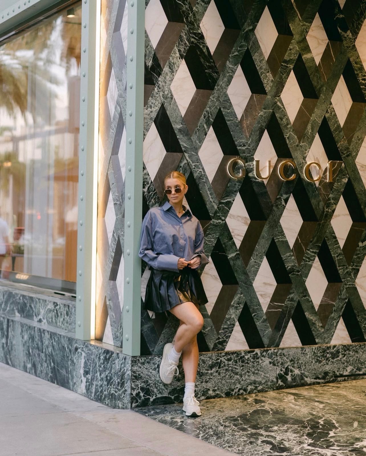 Street style portrait posed against a geometric Gucci storefront facade