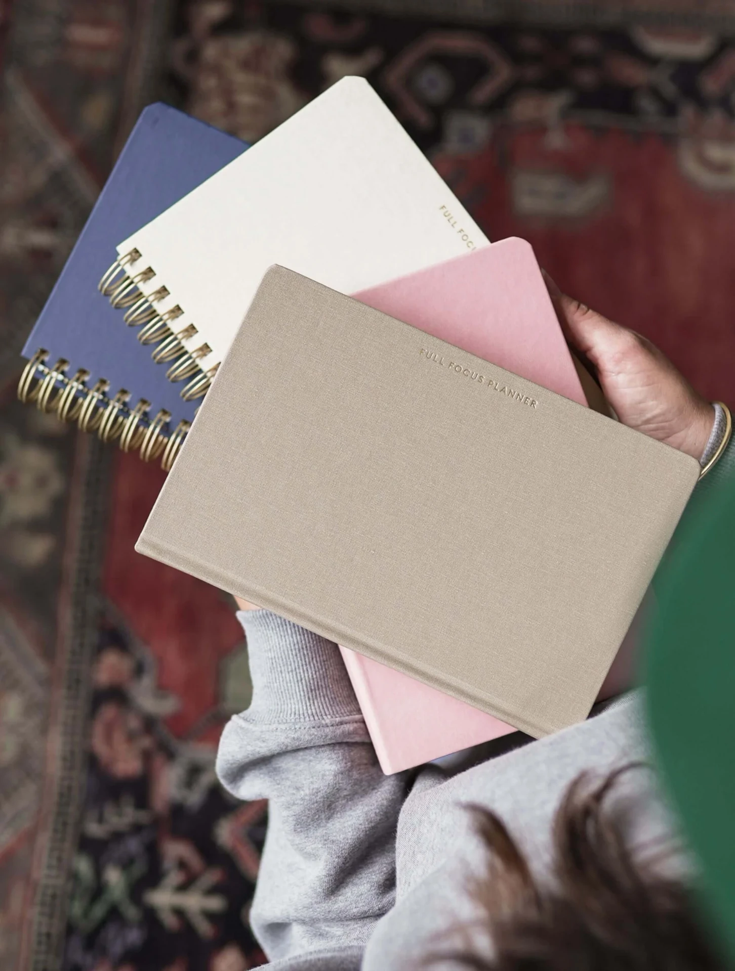 Overhead view of linen and paper Full Focus planners held over a Persian rug