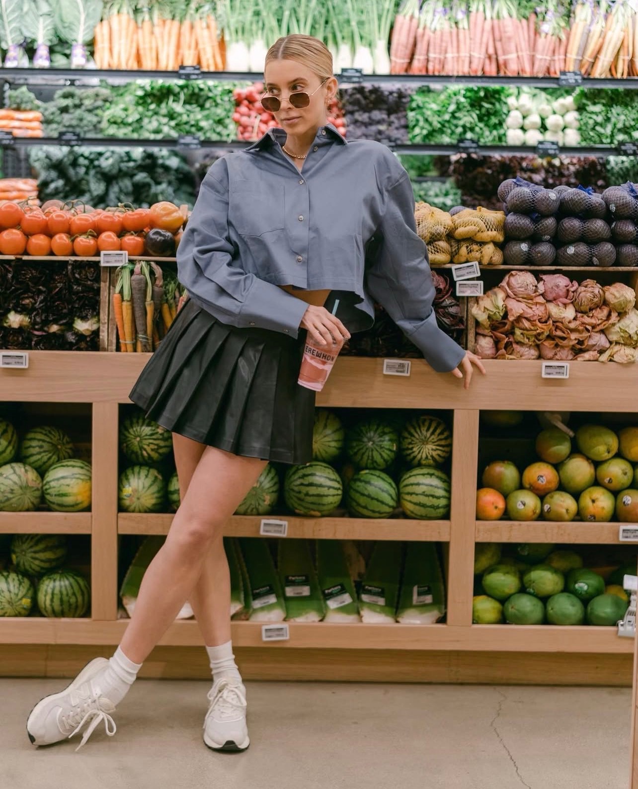 Fashion portrait inside a produce aisle holding a smoothie in front of colorful market displays